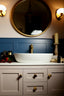 zenzar products in Bathroom vanity with round mirror, white sink, and blue wall.