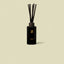 Black cherry diffuser bottle with wooden sticks on a beige background