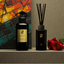 Zenzar RED ROSES collection diffuser and spray bottle with red roses on a shelf against a colorful brick wall.